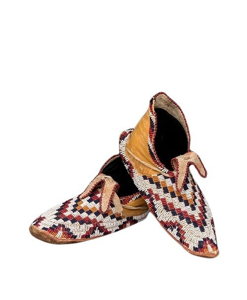 A pair of beaded moccasins with geometric and floral patterns, featuring hand-stitched details and handmade beads.