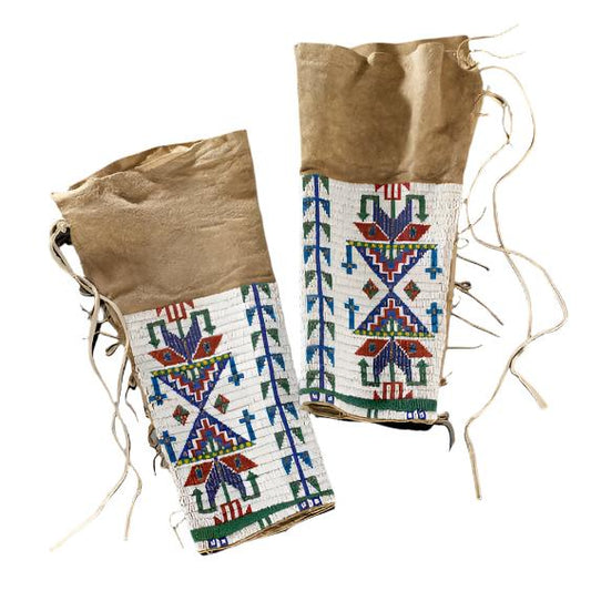 A pair of beaded leggings with intricate patterns and fringe, primarily in brown tones with white, black, and multicolored beads.
